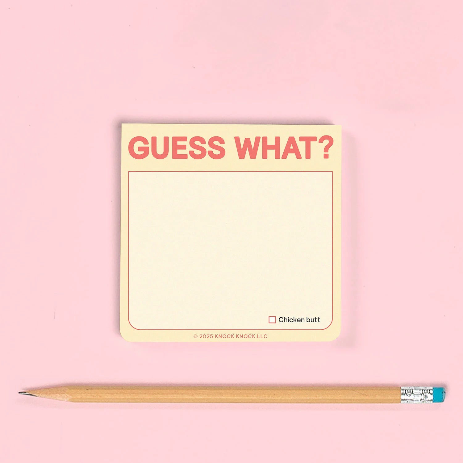 Notepad with 'Guess What?' text and a pencil on a pink background