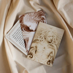 Two cards with artistic designs of faces on a beige fabric background