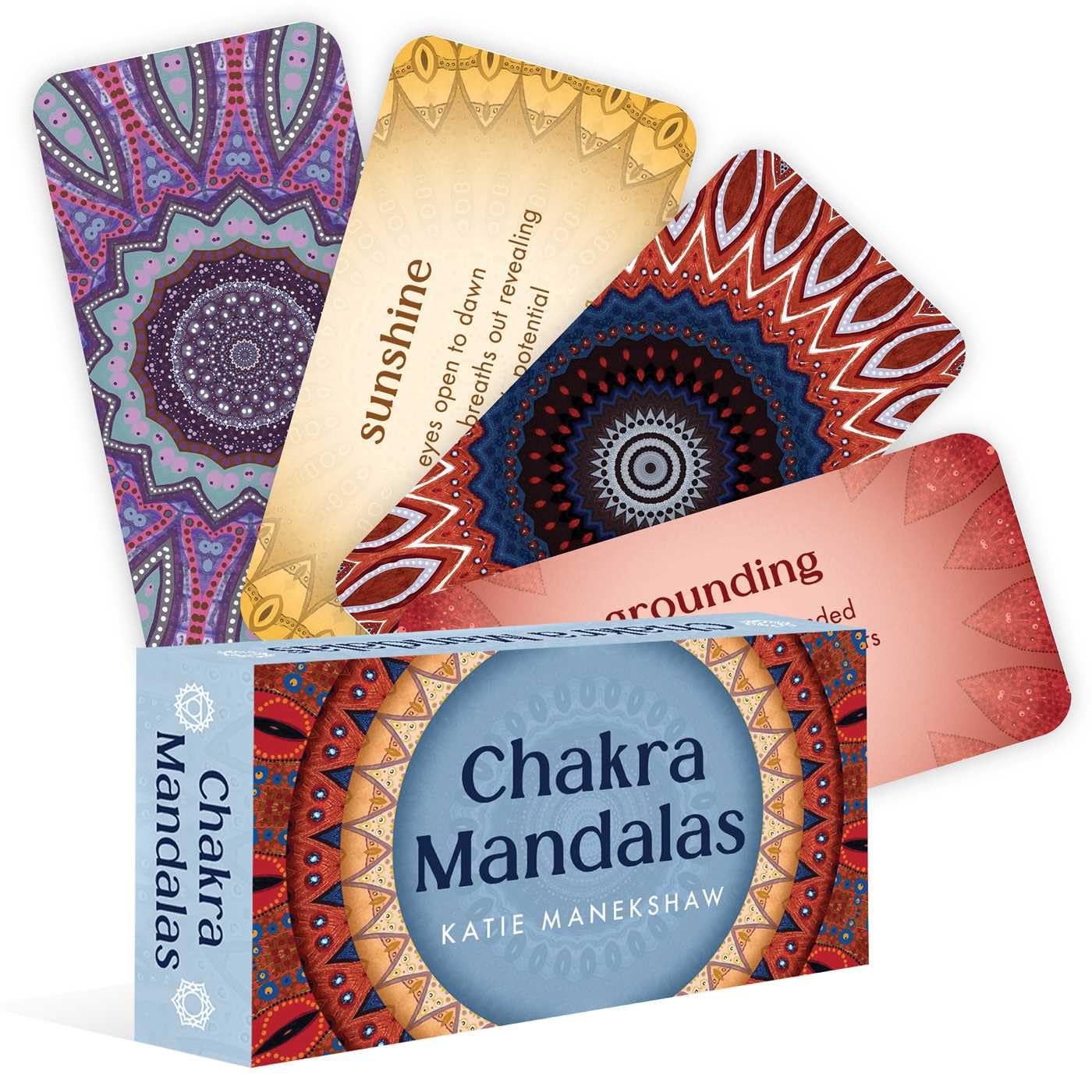 Chakra Mandalas mini deck By Katie Manekshaw Four Chakra Mandalas cards fan out from a box, each with colorful mandalas and titles like “sunshine” and “grounding.”