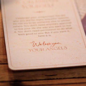 Card with 'We love you, YOUR ANGELS' text on a wooden surface