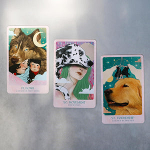 Three oracle cards with colorful illustrations of dogs and women, arranged on a silver surface.