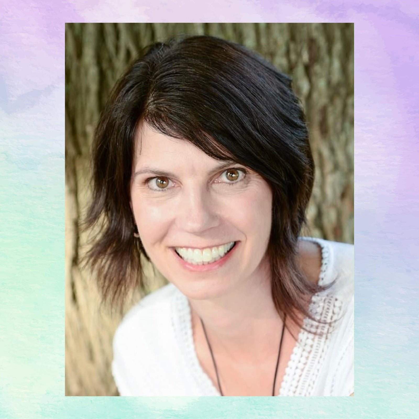Woman with shoulder-length brown hair smiling in front of a natural background
