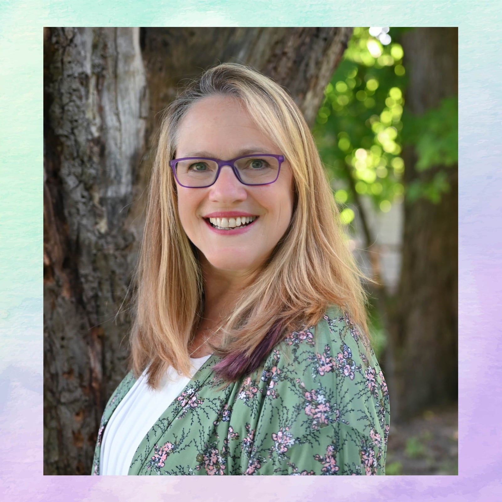 Woman with glasses standing outdoors next to a tree