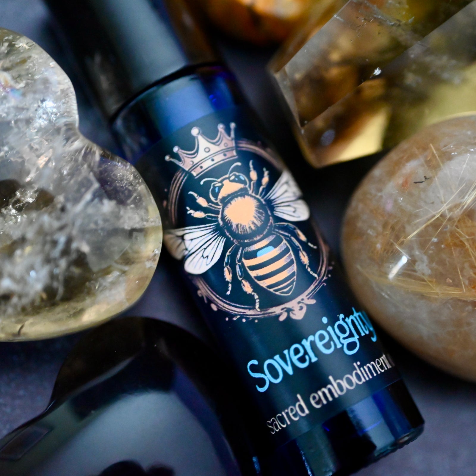 close up picture of roll on with back label with yellow bee on roll on bottle with crystals around