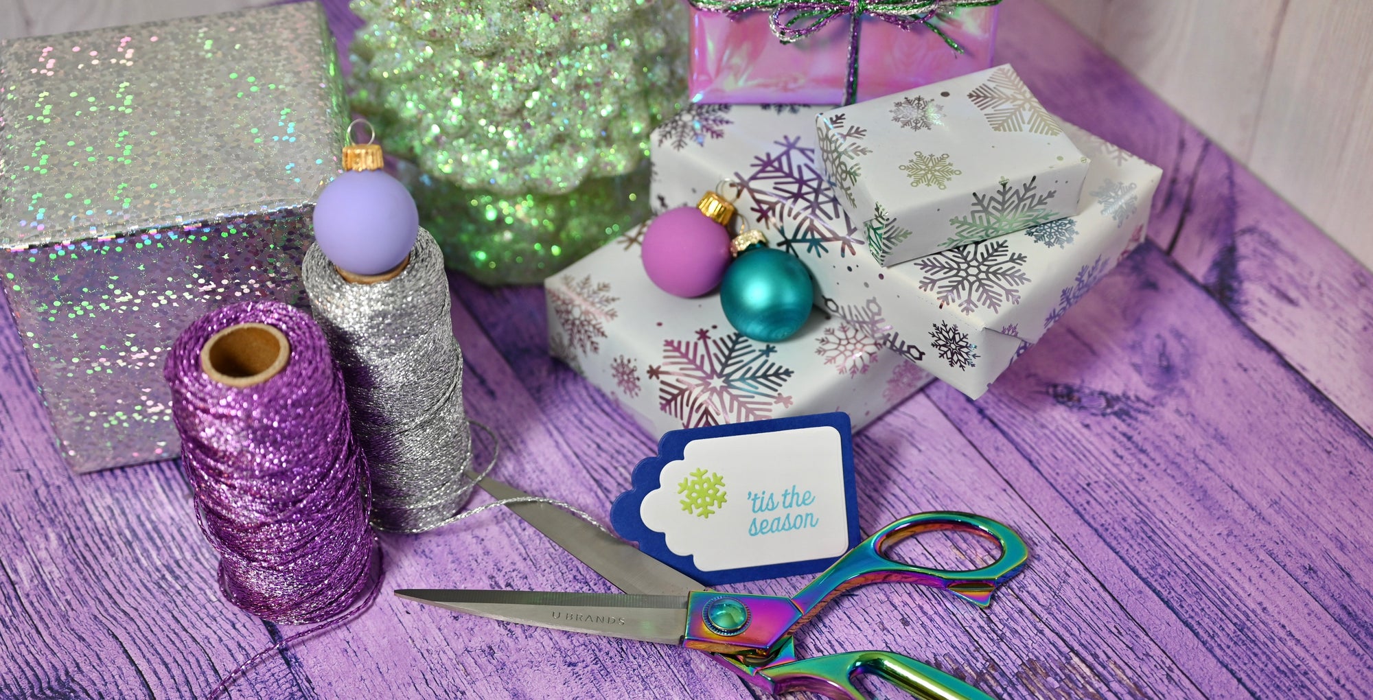 Decorative items including a box, ribbons, and ornaments on a purple surface.