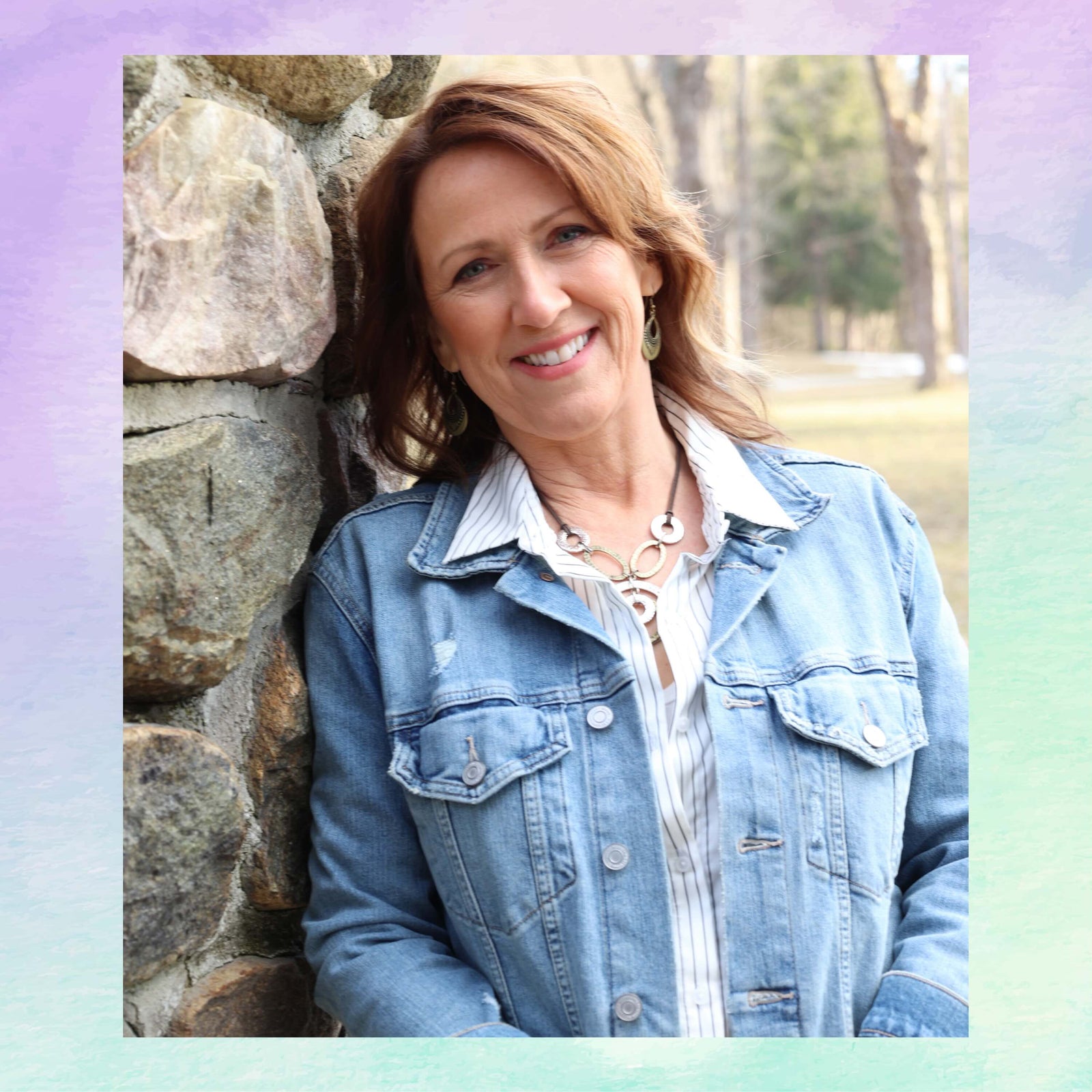 Woman wearing a denim jacket leaning against a stone wall outdoors