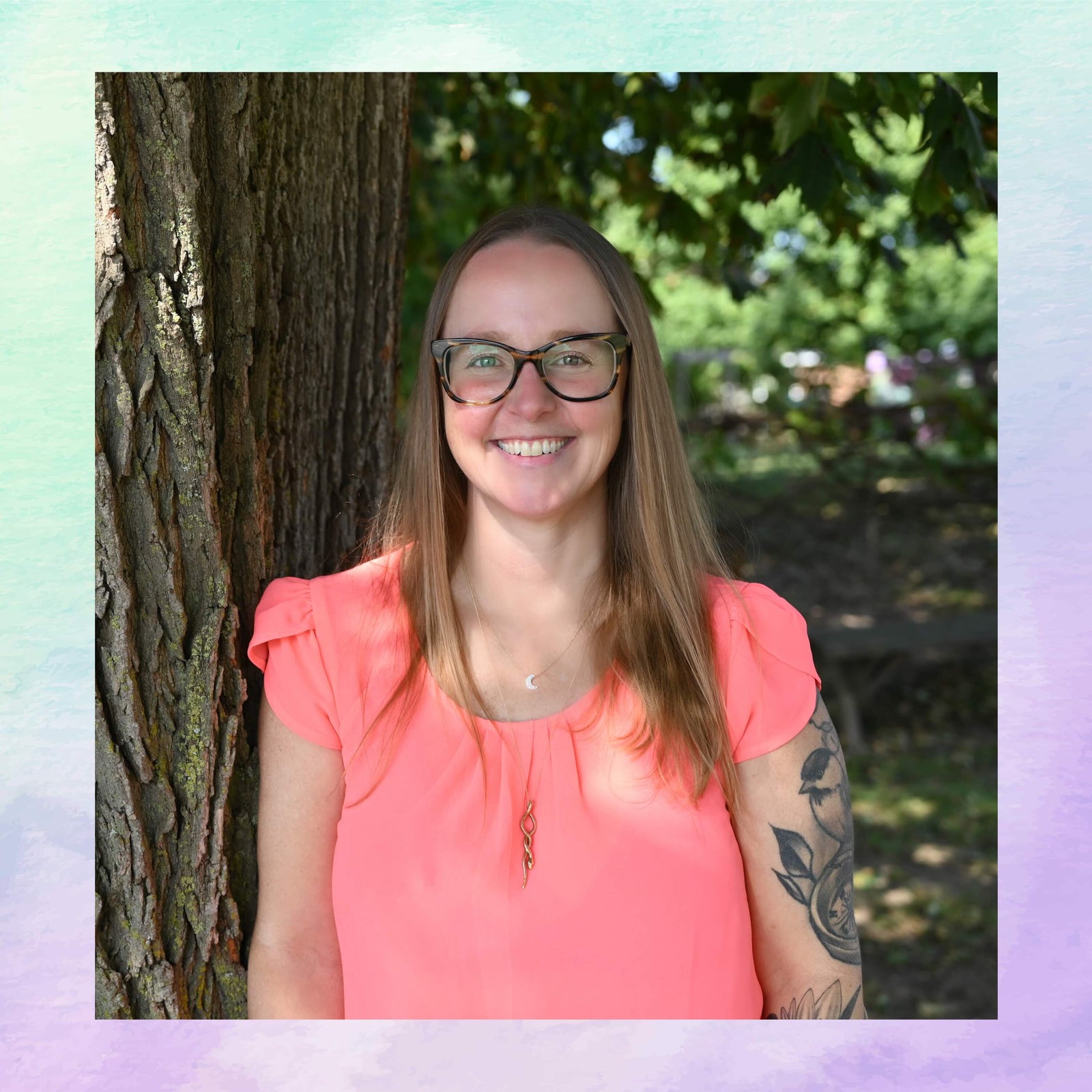 Woman with glasses and a pink shirt standing next to a tree