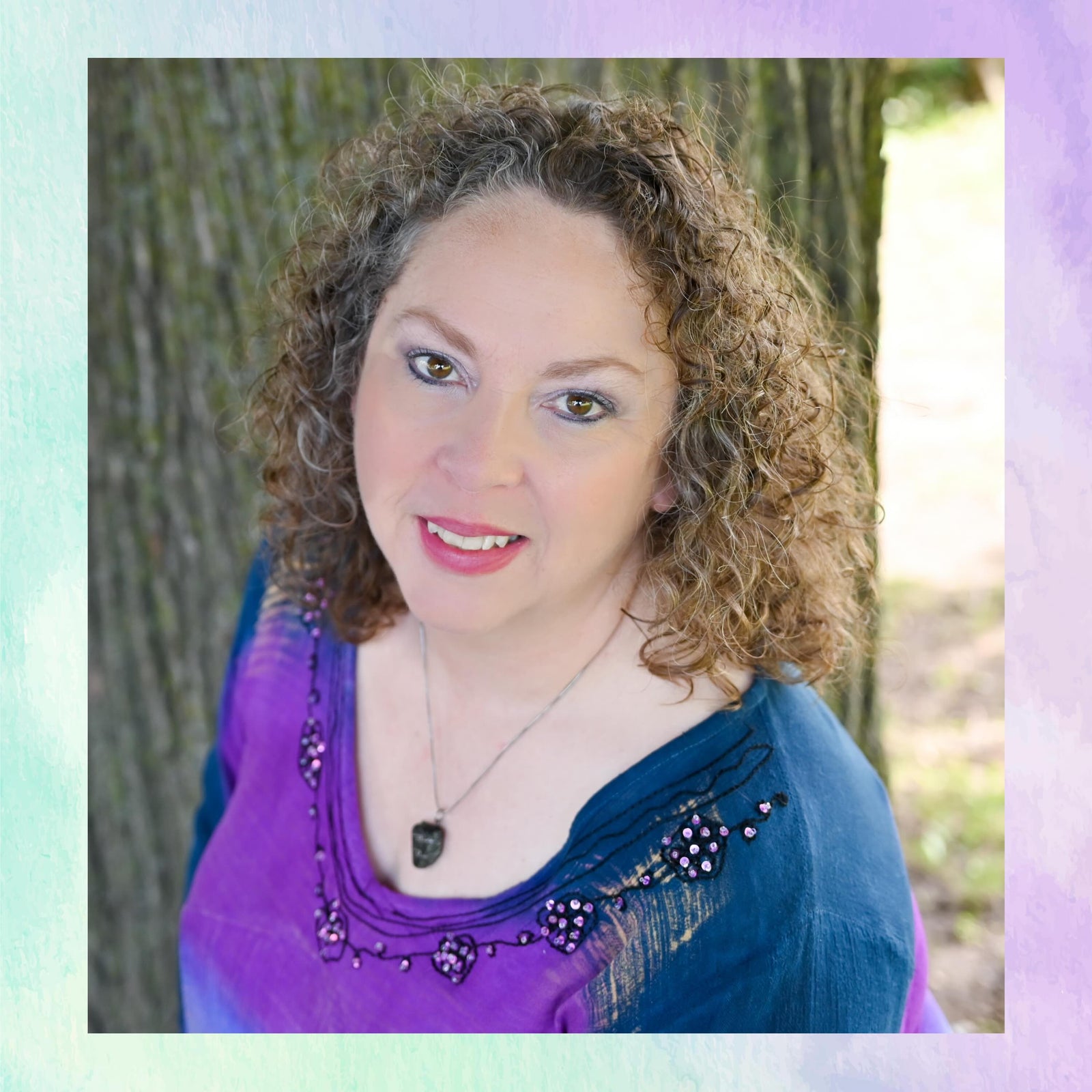 Woman with curly hair wearing a purple top with decorative sleeves in an outdoor setting