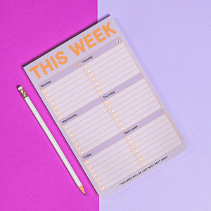 Weekly planner pad with a pencil on a pink and purple gradient background