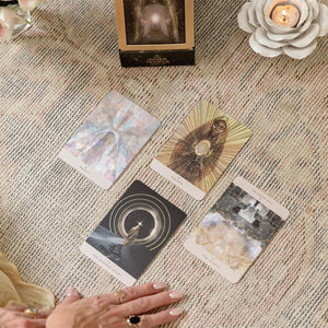 Four tarot cards on a textured surface with a hand reaching towards them.