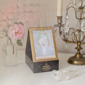 Decorative box with a card titled 'The Inner Temple Oracle' on a table with flowers and a candle.