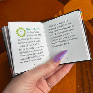 small Open book with text and a hand holding it on a wooden surface