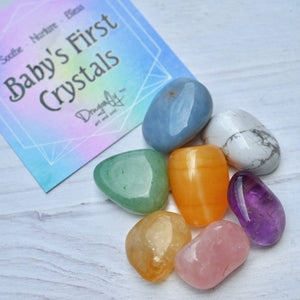 Colorful crystals on a white surface with a 'Baby's First Crystals' card in the background.