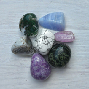Collection of various colorful stones on a light wooden surface