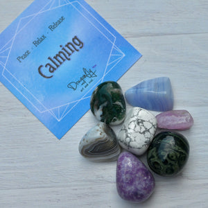 Set of polished stones with a 'Calming' card on a light wooden surface
