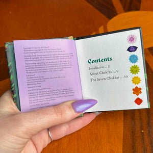small Open book with a purple cover held by a hand on a wooden surface