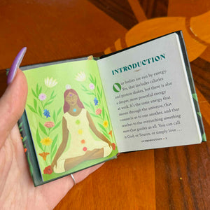small Open book with illustration of a woman and text on a wooden surface