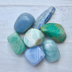 Collection of blue and green stones on a light wooden surface