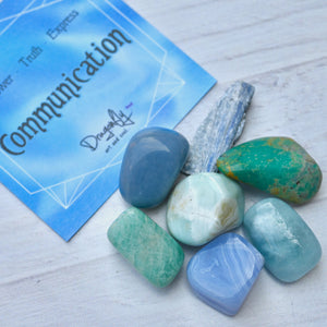 Blue and green stones on a white surface with a card labeled 'Communication' in the background.