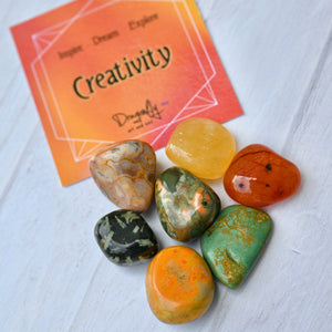 Colorful stones on a white surface with a 'Creativity' card in the background.