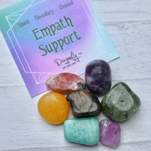 Colorful crystals and a card with 'Empath Support' text on a light wooden surface
