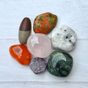 Collection of various colorful stones on a light wooden surface