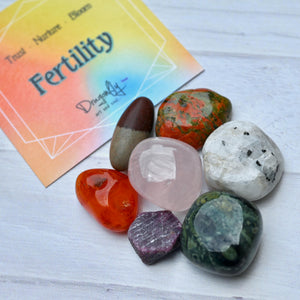 Colorful crystals on a white surface with a 'Fertility' card in the background