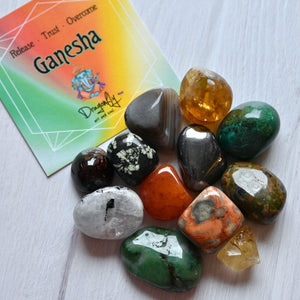 Colorful stones on a white surface with a Ganesha card in the background