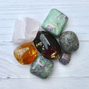 Collection of various colorful crystals on a light wooden surface