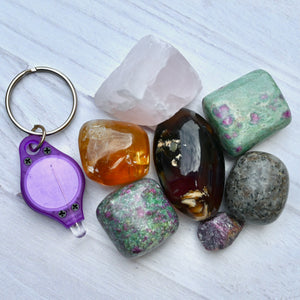 Collection of colorful crystals and a purple keychain on a light wooden surface