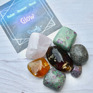 Collection of colorful crystals on a light wooden surface with a card in the background.