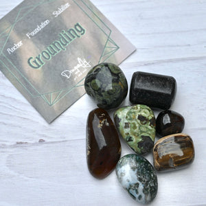Collection of tumbled stones with a card labeled 'Grounding' on a white surface.
