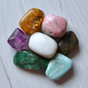 Assorted colorful stones on a light wooden surface