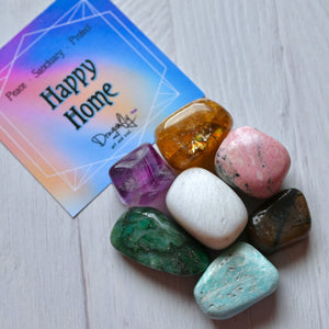 Colorful stones on a white surface with a 'Happy Home' card in the background