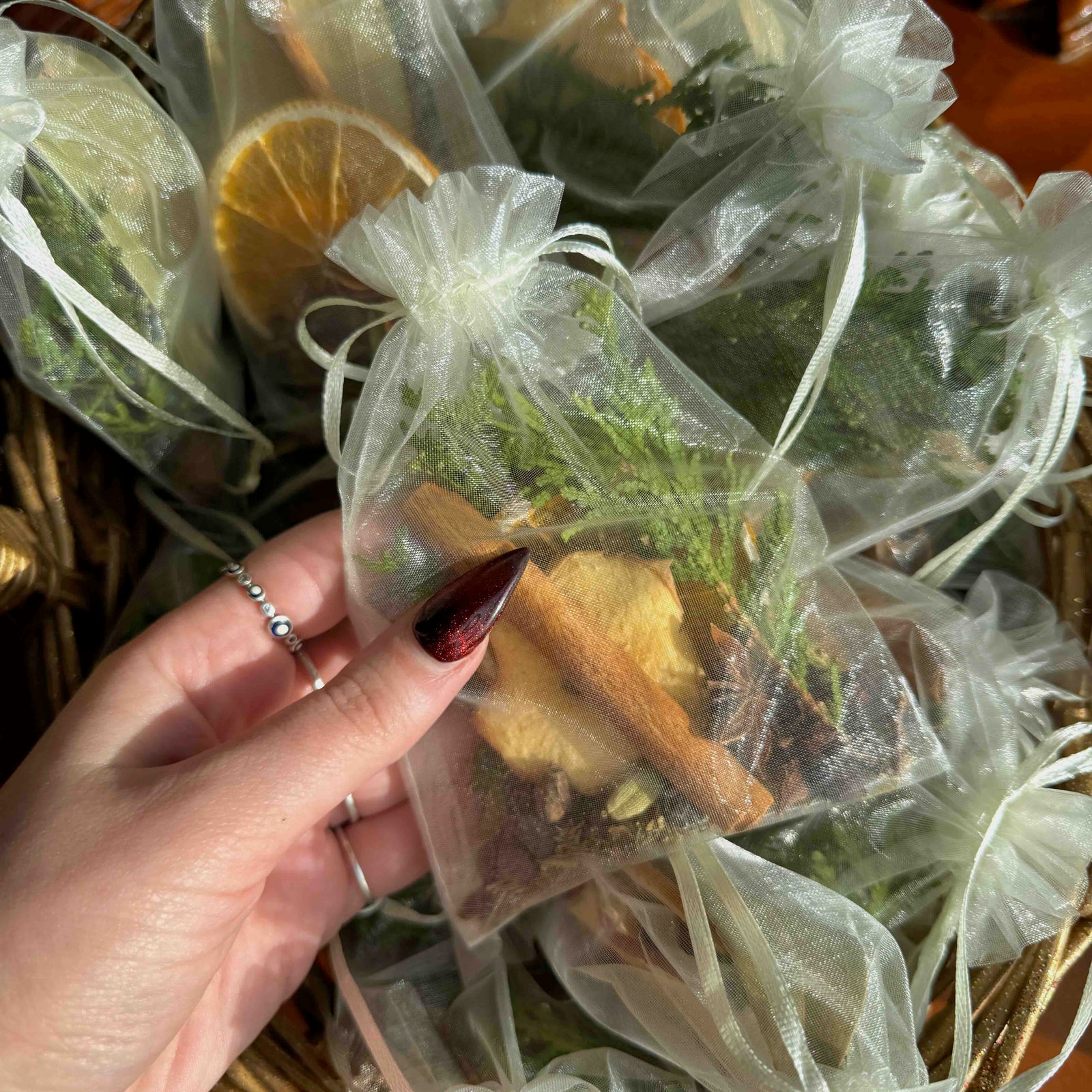 Hand holding a clear bag with dried herbs and spices, surrounded by similar bags.