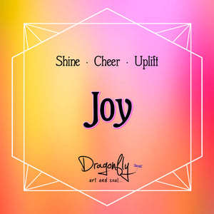Bright orange-pink label reads 'Joy – Shine · Cheer · Uplift'. Includes Dragonfly logo.