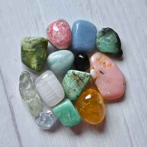 Assorted colorful stones on a light wooden surface