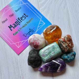 Colorful crystals and a motivational card on a white surface