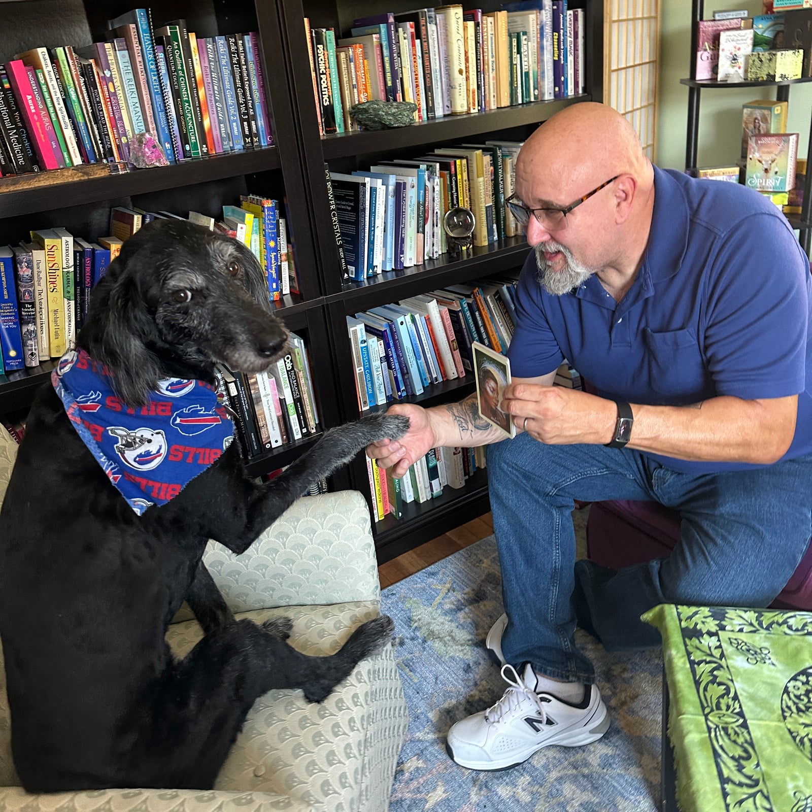 black dog and man sitting in chairs man holding dogs paw showing a card