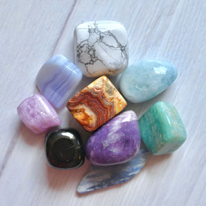 Collection of multicolored gemstones on a light wooden surface