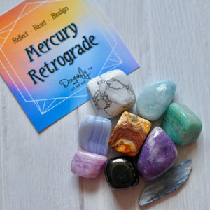 Colorful crystals on a white surface with a card titled 'Mercury Retrograde' by Dragonfly.