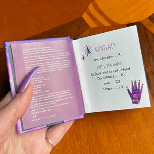small Open book with purple cover and white text on a wooden surface