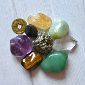 Collection of various crystals and a gold coin on a light wooden surface