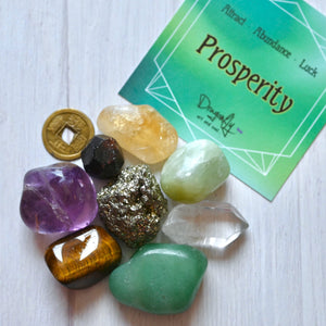 Collection of colorful crystals and a green card with 'Prosperity' text on a white surface.