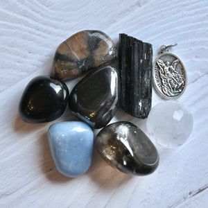 Collection of various stones and a silver pendant on a textured white surface