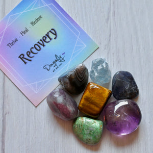 Colorful crystals on a white surface with a 'Recovery' card in the background