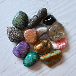 Collection of multicolored polished stones on a textured white surface