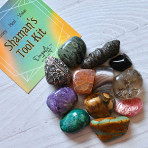 Collection of colorful stones with a 'Shaman's Tool Kit' card on a white surface