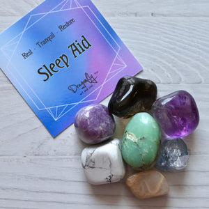 Colorful crystals on a white surface with a 'Sleep Aid' card in the background