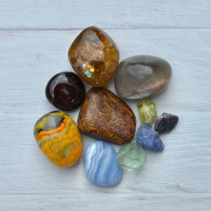 Collection of multicolored gemstones on a light wooden surface